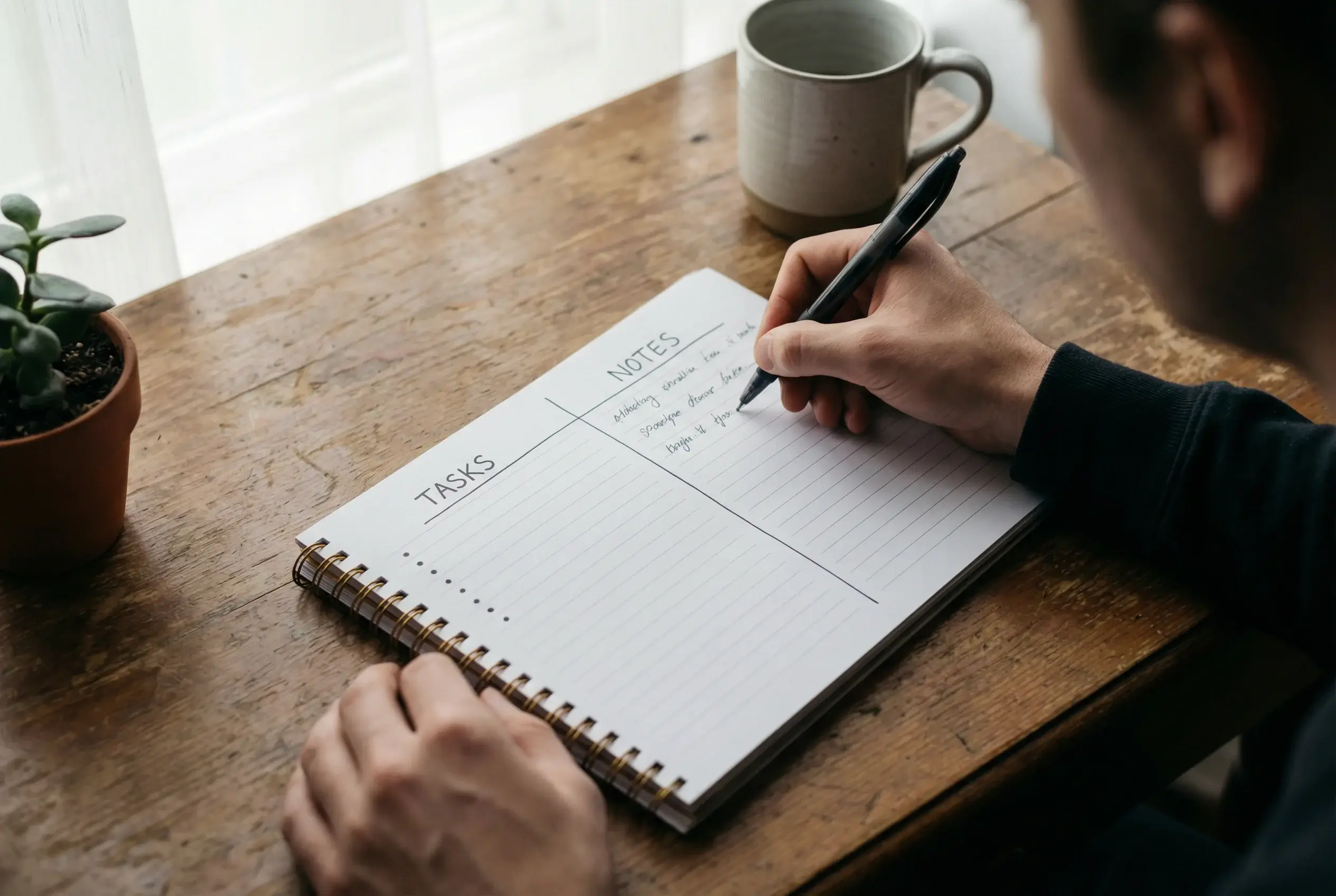 Pessoa fazendo anotações em caderno com divisão em duas colunas
