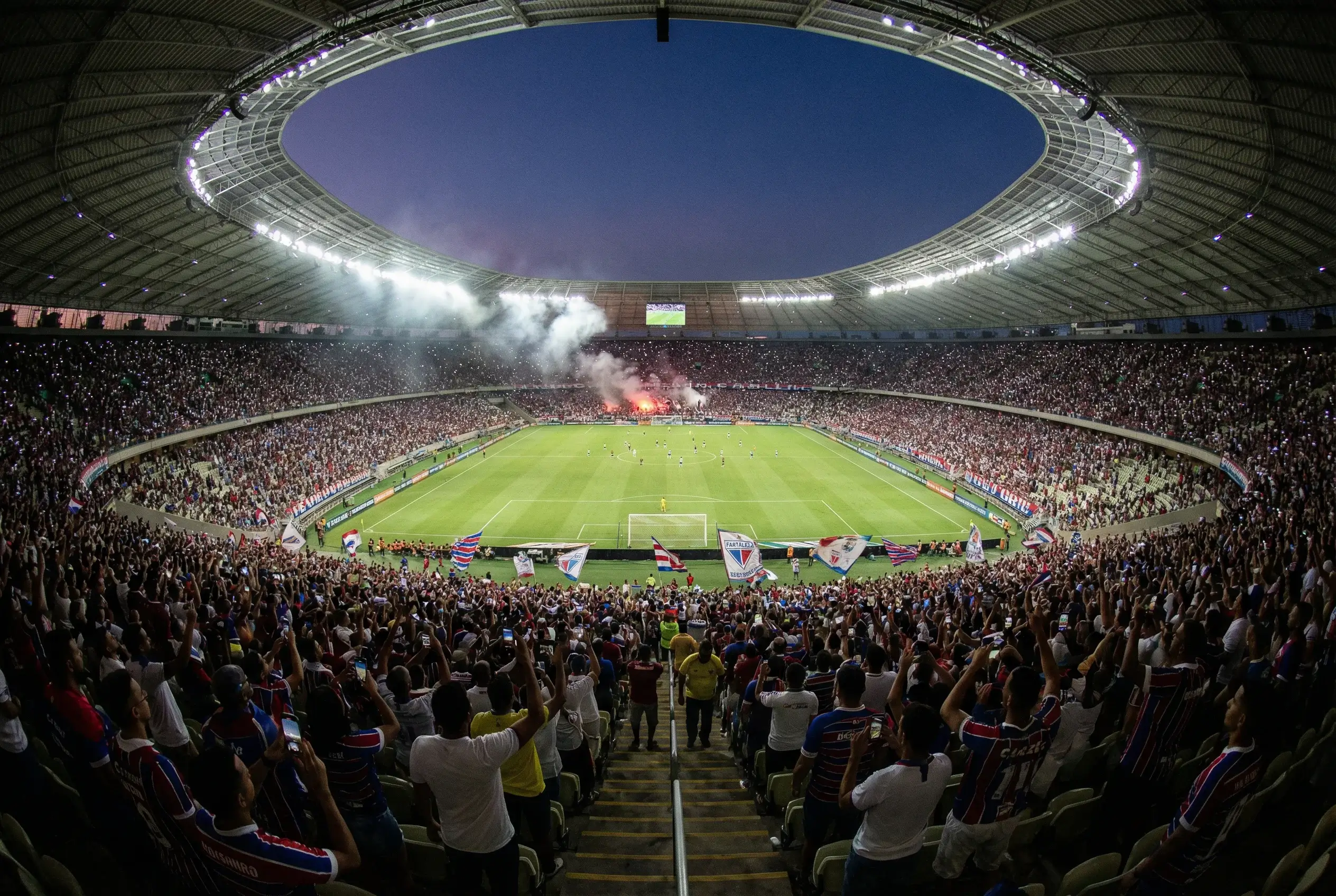 Visão panorâmica de estádio de futebol brasileiro lotado durante partida