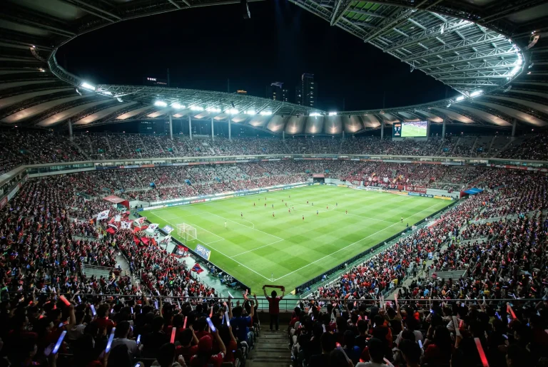 Estádio de futebol asiático moderno lotado durante partida noturna