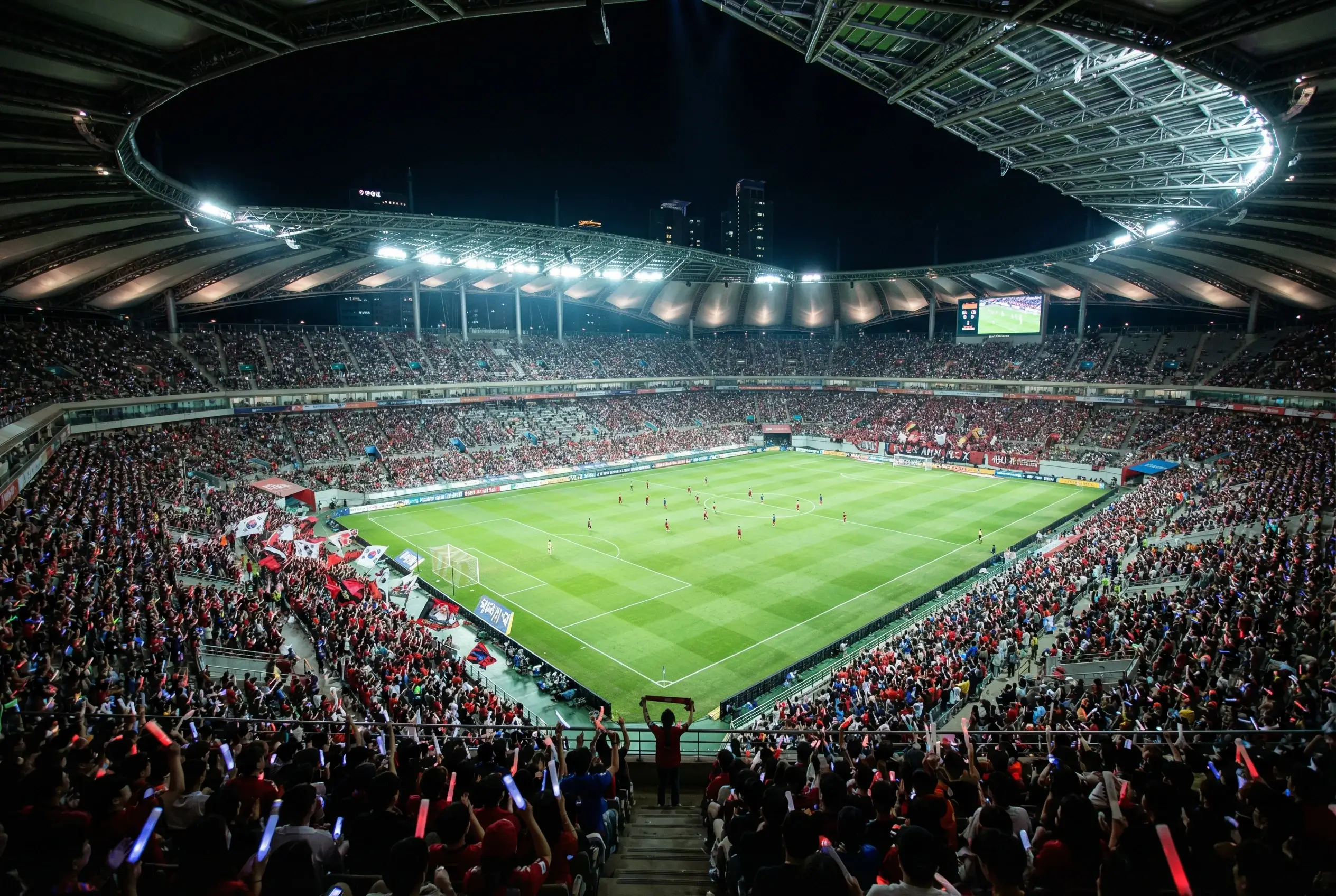 Estádio de futebol asiático moderno lotado durante partida noturna
